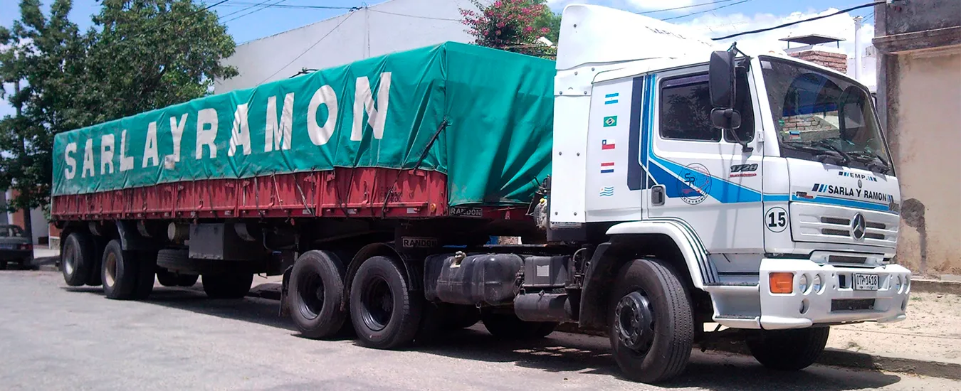 Semirremolque de Sarla y Ramón con carga seca cubierta por lona verde rotulada con el nombre de la empresa
